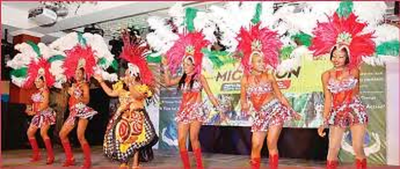 Dancers performing on stage in white and red plumes